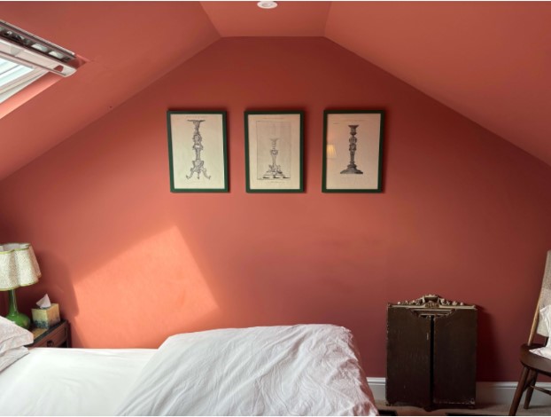 Terracotta bedroom wall styled with framed prints above a bed
