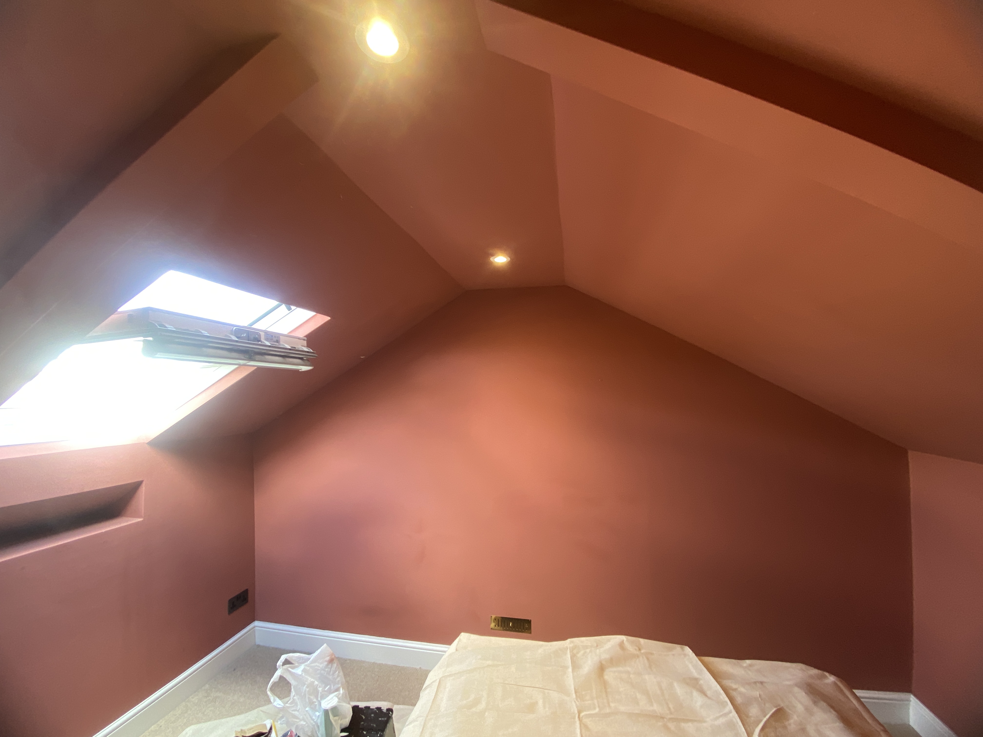 Terracotta-painted loft bedroom with a skylight